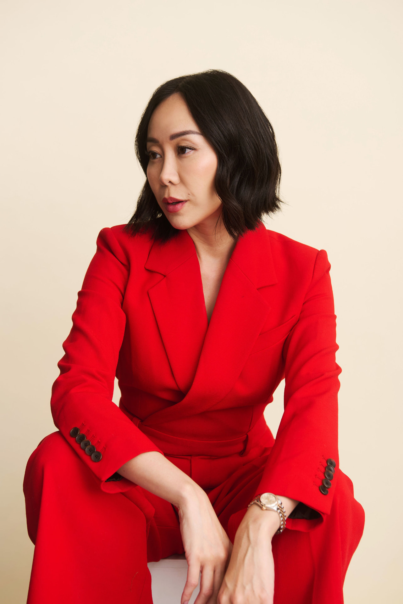 Amy Chan in a red suit against a cream background