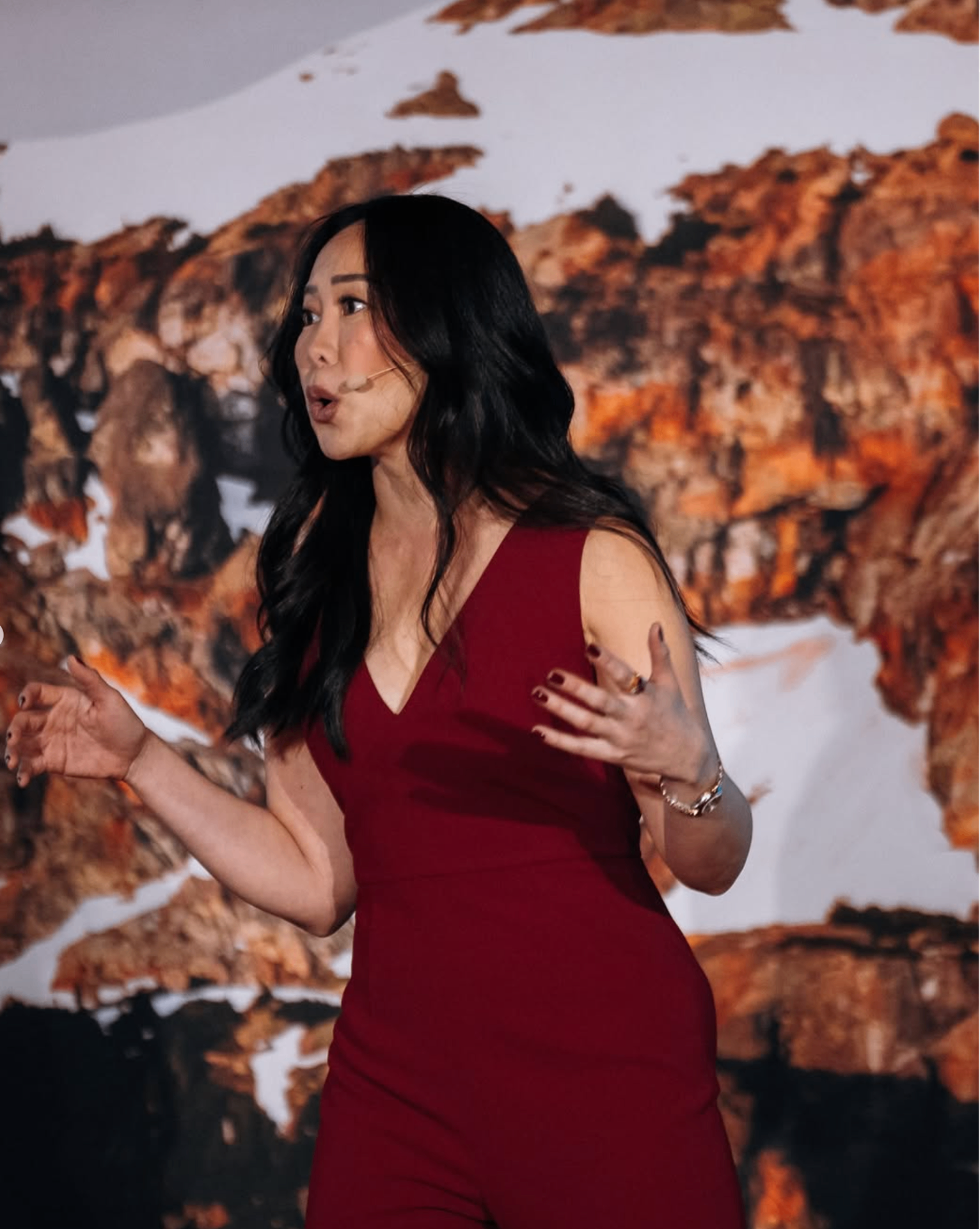 Amy Chan speaking on stage in a red dress